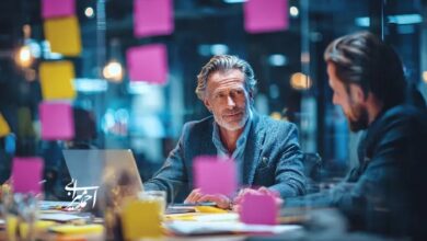 جلسه کوچینگ مدیریتی در فضای اداری مدرن؛ گفت‌وگوی دو مدیر کنار لپ‌تاپ و یادداشت‌های چسبی برای شفاف‌سازی اولویت‌ها و تصمیم‌گیری نتیجه‌محور.