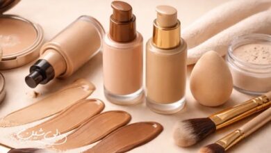 لوازم آرایشی مرتبط با کرم‌پودر شامل بطری‌های کرم‌پودر در چند تناژ مختلف، سواچ‌های رنگی روی سطح، پودر فیکس، اسفنج آرایشی و براش‌ها در یک چیدمان مینیمال و روشن